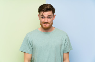 Obraz premium Redhead man over colorful background having doubts and with confuse face expression