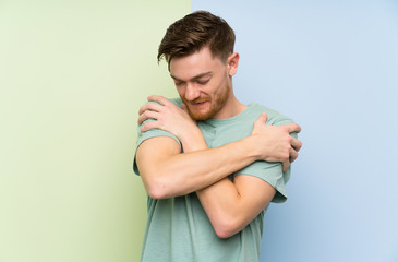 Redhead man over colorful background hugging