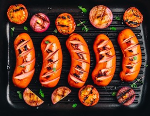 Grilled sausages and vegetables in cast iron pan closeup.