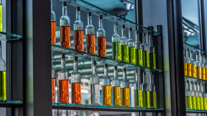 Flaschen mit bunter Flüssigkeit in einem Regal mit Glasböden