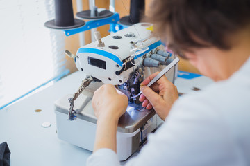 Professional tailor, fashion designer sewing clothes with sewing machine at atelier, studio. Fashion and tailoring concept