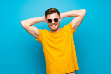 Fototapeta premium Redhead man over blue wall with glasses and happy