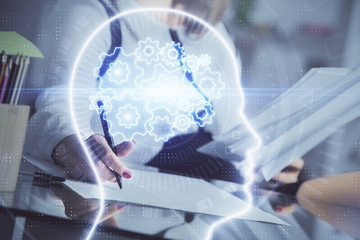 Multi exposure of woman's writing hand on background with brain hud. Concept of learning.