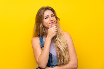 Obraz premium Young blonde woman with overalls over isolated yellow background laughing