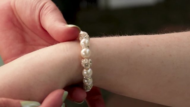 Close-up of rolling bracelet up a woman's arm.