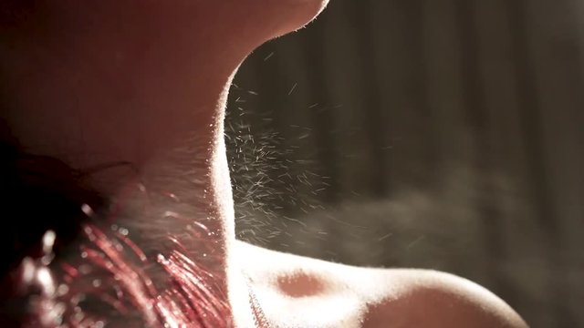 Close-up of a woman spraying perfume on her neck.