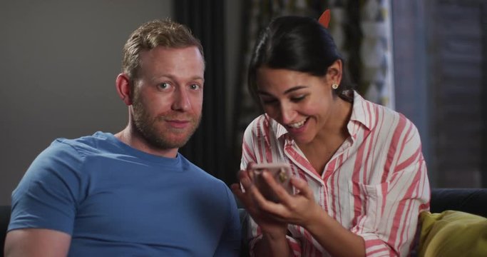 4K Girl excitedly showing boyfriend her smartphone & man looking at camera bored