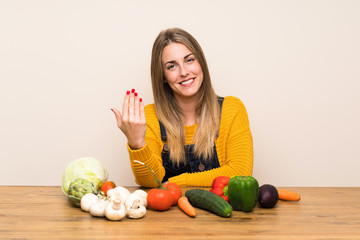 Fototapeta premium Woman with lots of vegetables inviting to come