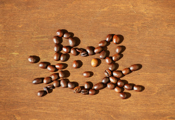 Roasted coffee beans in a shape of cat's face on wooden background,  photo, coffee background