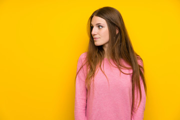 Obraz premium Young woman with long hair over isolated yellow wall making doubts gesture looking side