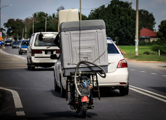 Mopedfahrer  auf einer Straße in Thailand transportiert eine Waschmaschine