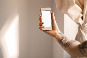 phone with white screen cut in the hand with a tattoo on a light background closeup prints the text