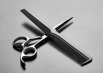 Comb for hair and scissors lying on the table. Barber scissors and comb on a dark background....