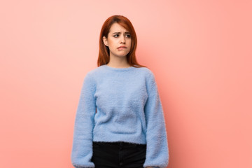 Fototapeta premium Young redhead woman over pink background with confuse face expression while bites lip
