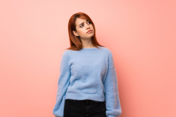 Obraz premium Young redhead woman over pink background looking up with serious face
