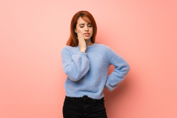 Young redhead woman over pink background with toothache