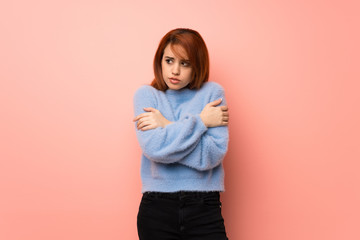 Young redhead woman over pink background freezing