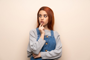 Young redhead woman over isolated background having doubts while looking up