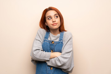 Young redhead woman over isolated background making doubts gesture while lifting the shoulders