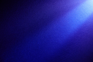 Dark blue beam of light shining from top to bottom on a dark background.