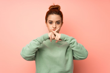 Young redhead woman with sweatshirt showing a sign of silence gesture