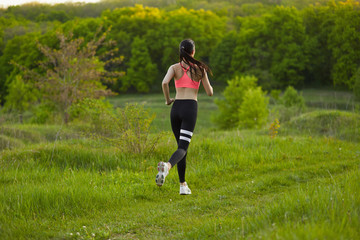 Sexy, sporty girl with a beautiful figure wearing a sports brassiere and leggings, doing sport exercises, outdoor running