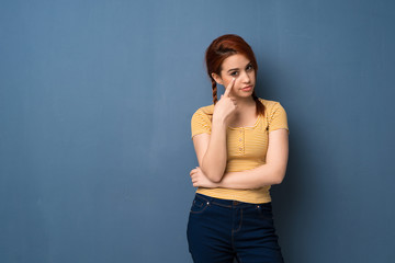 Young redhead woman over blue background looking to the front