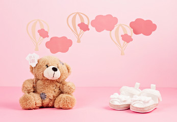 Baby girl cute pink shoes over the pink pastel background with clouds and ballons