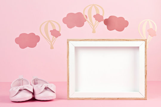 Baby girl cute pink shoes over the pink pastel background with clouds and ballons