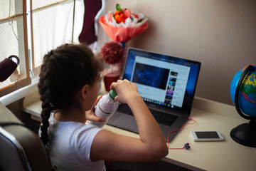 Little girl looking in laptop with thermo bottle for water in hand