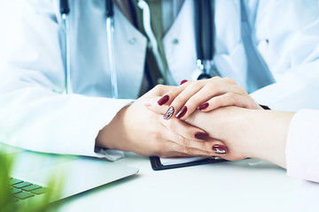 Cropped image of female therapist holding patient's hands during the consultation. Medical ethics...
