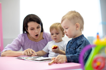 Obraz na płótnie Canvas Babysitter reads book to kids in nursery