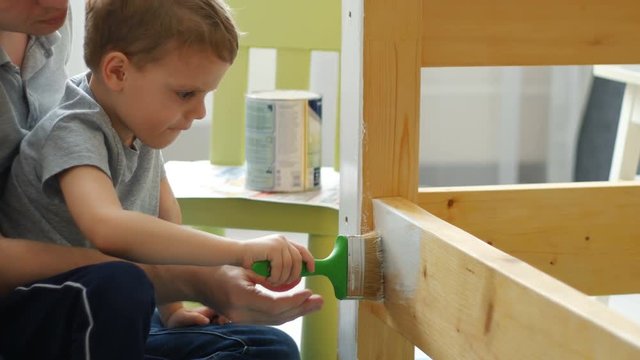 Farher and son are Painting And Varnishing Wood Boards In White Color With Paintbrush