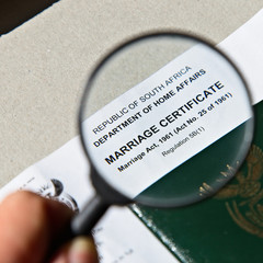 A hand holding an official South African marriage certificate. Getting married in court (home affairs) concept image. 