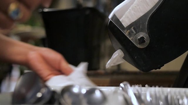 woman takes napiks from dispenser in slow motion. Close up on a woman's hand as she takes several white paper napkins from a dispenser next to silverware in slow motion.