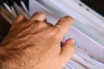 A Caucasian man looking inside a filing cabinet for tax records.  Administration concept image.  