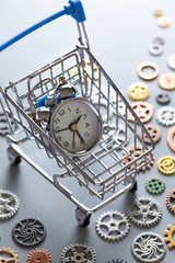 Small alarm clock in shopping cart and small parts of watch