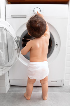 Baby pushing buttons of washing machine
