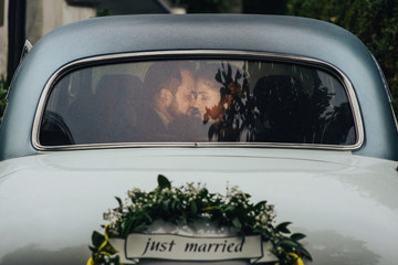 Happy luxury wedding couple kissing and embracing near retro car. 