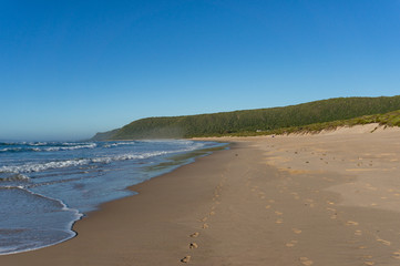 Empty sand beach landscape with waves and sand with footprints