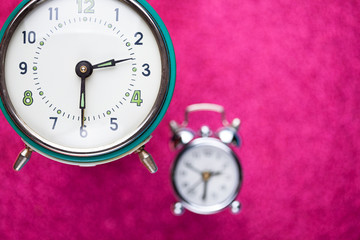 Retro alarm clock on pink abstract background