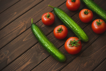 Cucumbers and tomatoes on a wooden flat surface