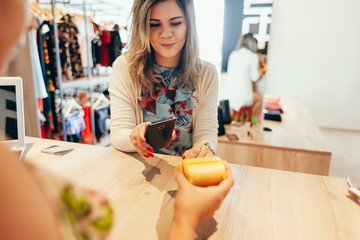 Woman paying with NFC technology on mobile phone, restaurant, cafe, bar, clothing store