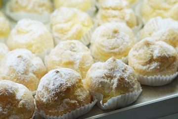 Cream puffs with powdered sugar at the window display of bakery shop.