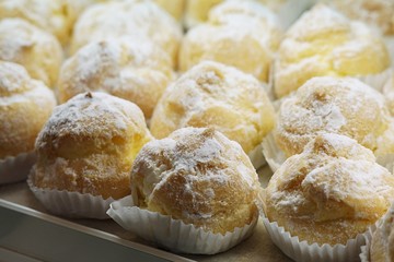 Cream puffs with powdered sugar at the window display of bakery shop.