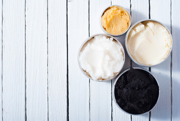 shea, macadamia nut and coffee butter, black cosmetic mud on white wooden table background