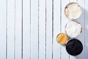 shea, macadamia nut and coffee butter, black cosmetic mud on white wooden table background
