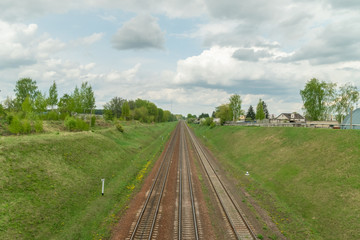 railway goes through the green field, the sky with clouds