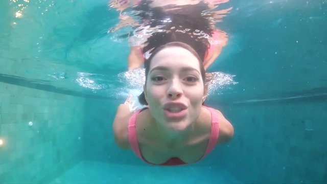 Beautiful girl relaxing outdoor in her garden with swimming pool, swimming underwater