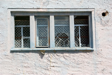 Exterior of an old abandoned cottage with broken glass and white cracked wall